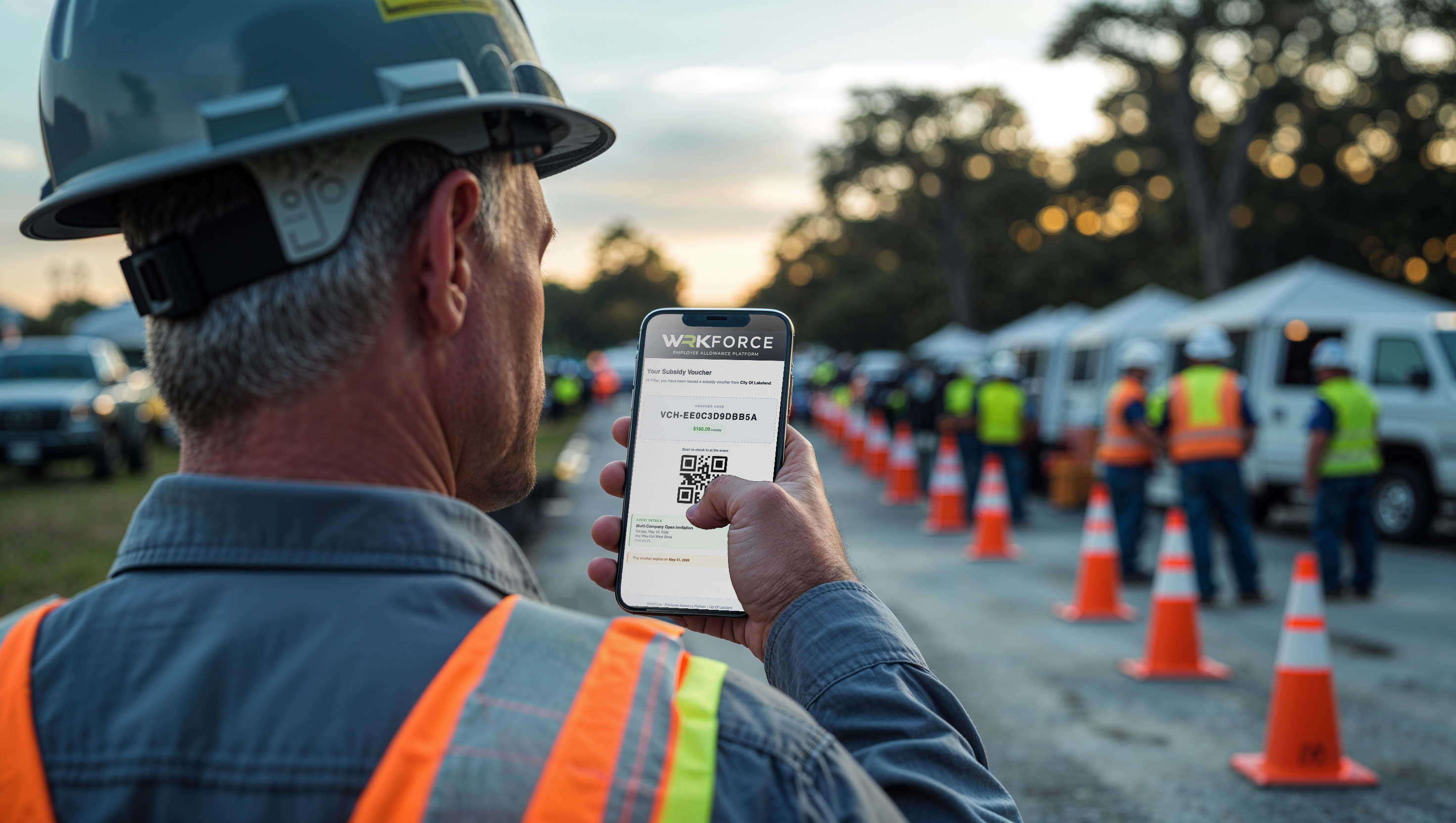 An employee in a hard hat viewing a workboot voucher on his phone at an on-site event