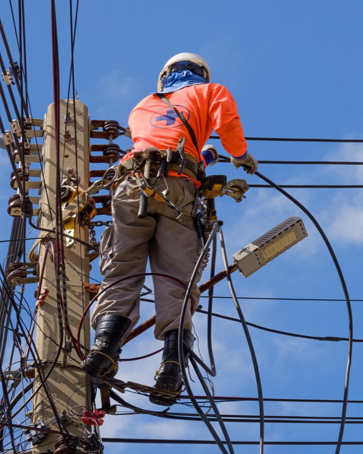 Lineworker in safety gear repairing overhead power lines